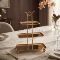 Polished gold metal three-tier serving stand with ring handle and ball feet