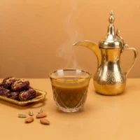 Cawa cup beside a coffee pot and dates in a styled serving scene
