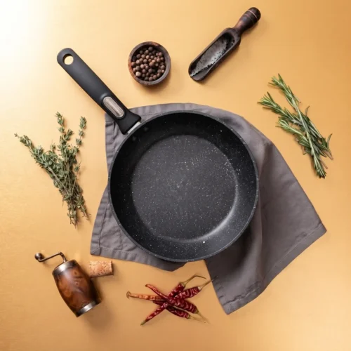 Top-down view of a black speckled nonstick frying pan with a long handle and hanging hole