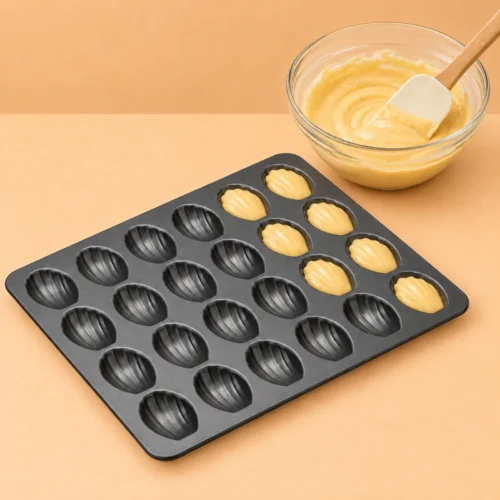 Mini Madeleine Pan, 24 Cavities, Non-Stick Mini madeleine pan shown with batter in several shell-shaped cavities