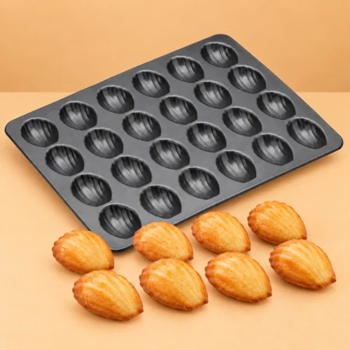 Mini Madeleine Pan, 24 Cavities, Non-Stick Dark grey madeleine pan displayed beside finished shell-shaped cakes